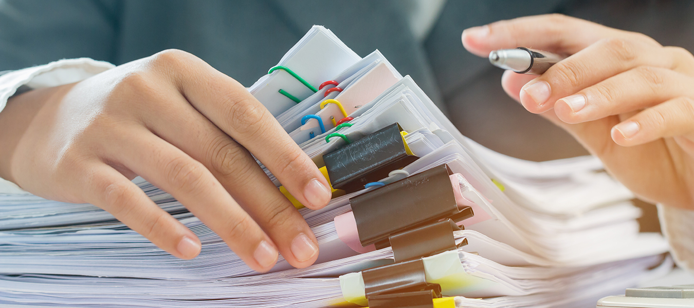 Hands organizing stacked paperwork with binder clips